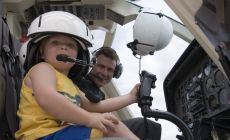 toddler sitting in passenger seat of helicopter with Dad in pilot's seat